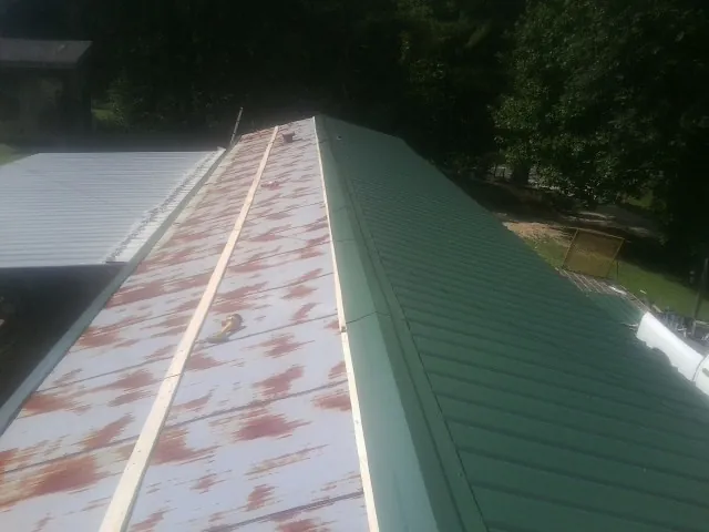 Old rusted panels beside newly installed green metal roofing — Wind Damage Roof Repair by Roofing Brothers in Willow City