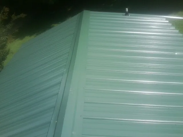 New green metal panels meeting at the ridge of a roof — Flat Roof Repair work by our crew in Willow City