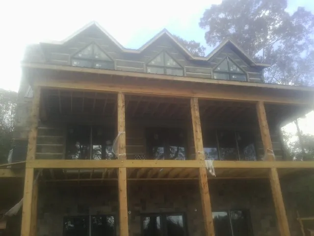 Dormers and porch framing on a large log home under construction — Roof Coating work by our crew in Willow City