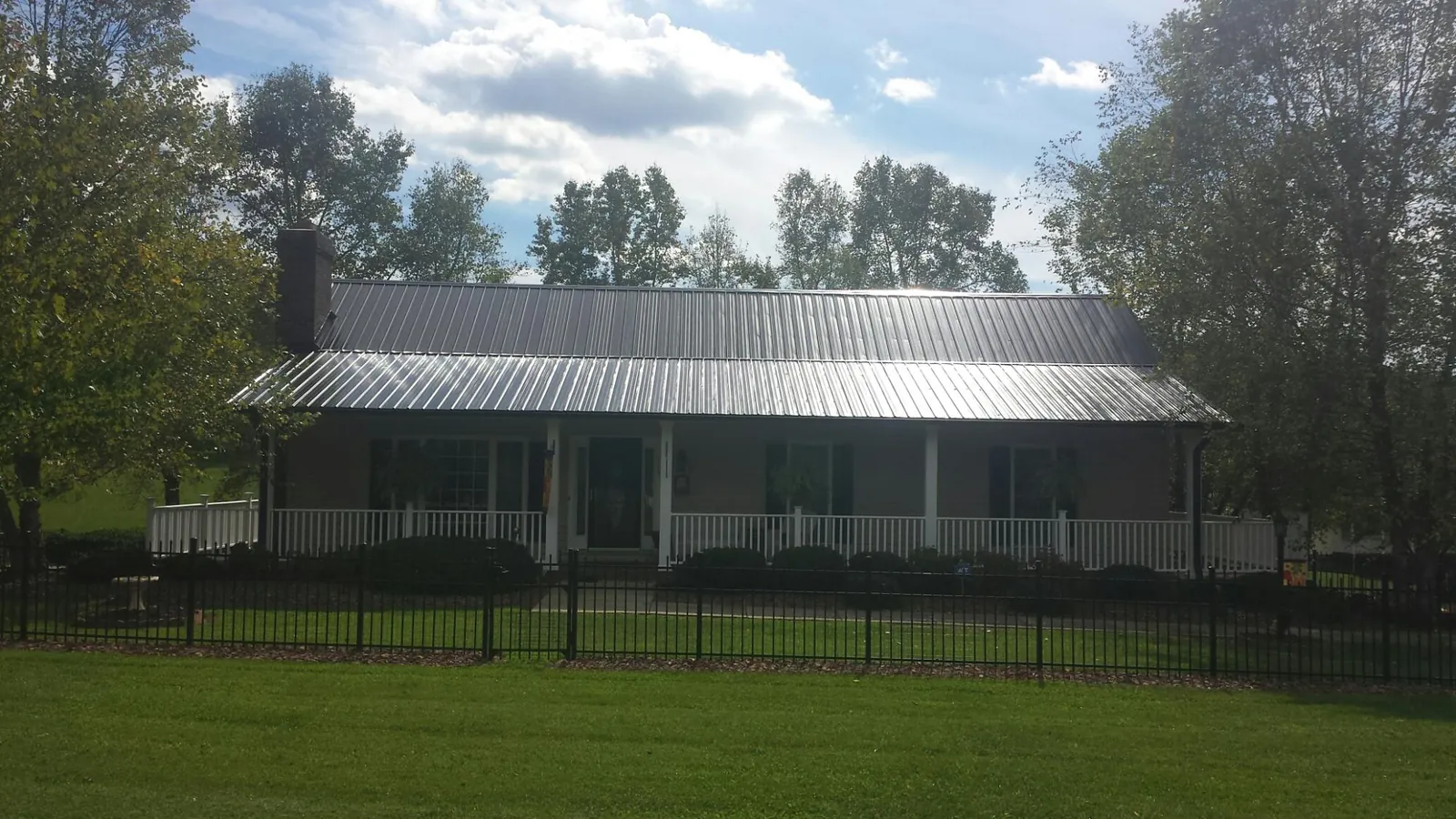 Gray metal roof on a brick ranch with a full width front porch — Gutter Guard Installation work by our crew in Willow City