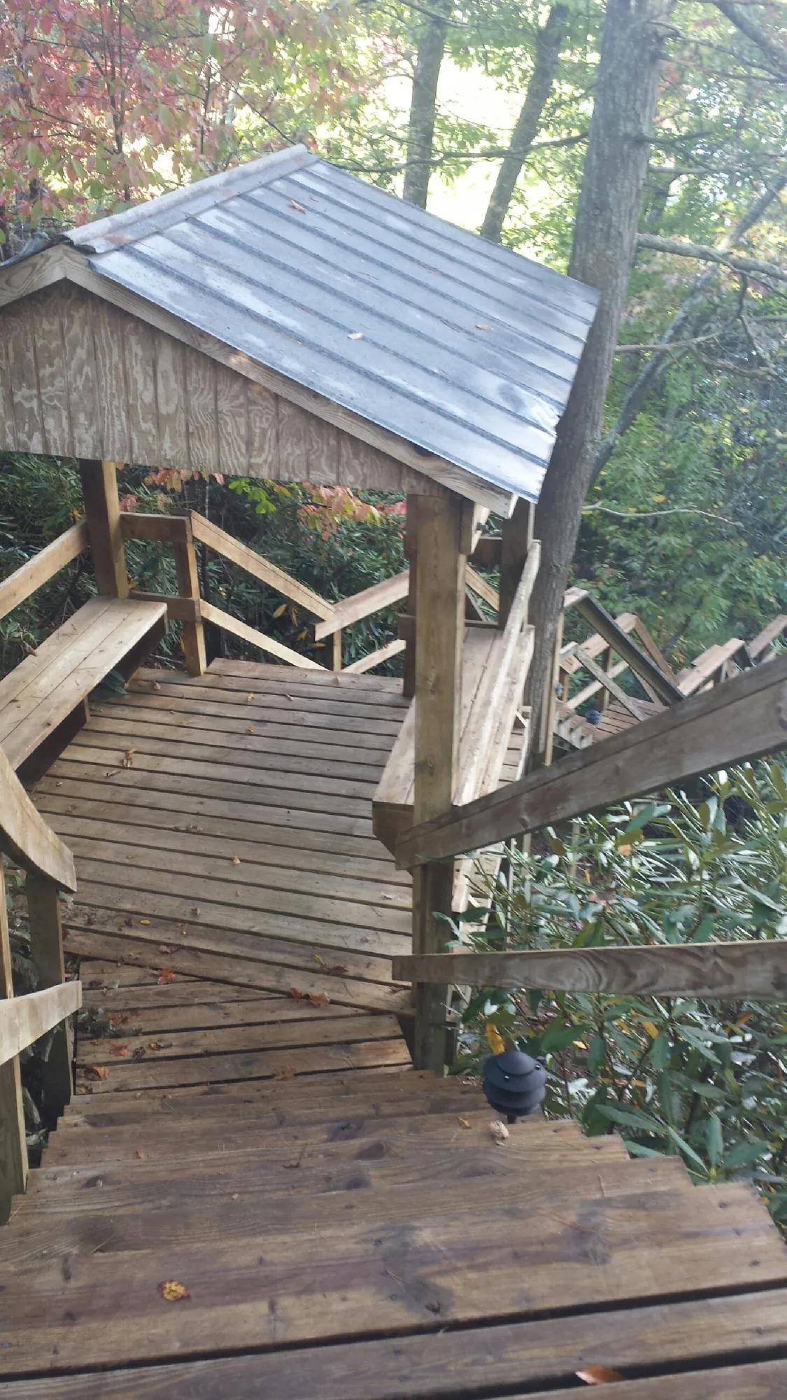 Metal roofed shelter over wooden steps on a wooded walkway — Skylight Repair & Installation work by our crew in Willow City