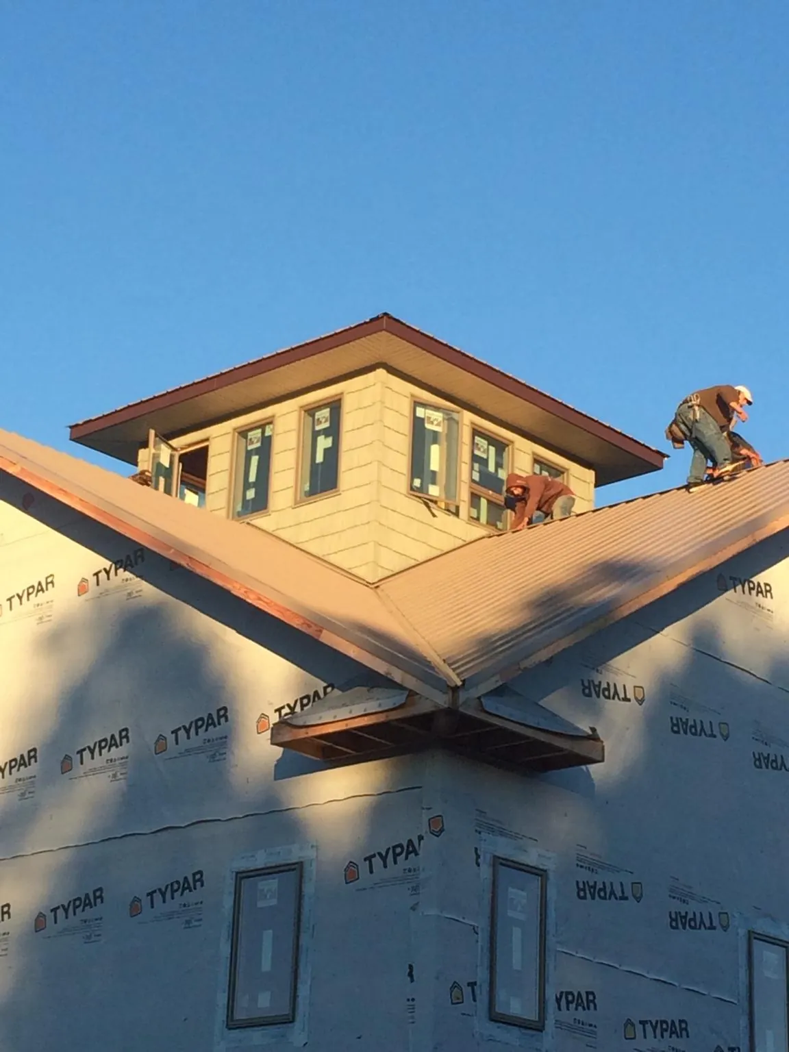 Roofers working around a rooftop cupola on a new metal roof at sunset — Roof Waterproofing in Willow City by Roofing Brothers